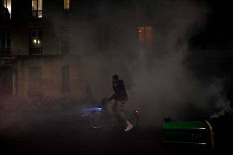Pyöräilijä pyöräili kyynelkaasun läpi mielenosoitusten aikaan Pariisissa lauantaina.