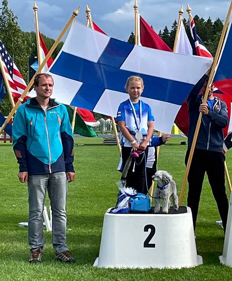 Anni Koskelma ja kääpiövillakoira Kiero pääsivät poseeraamaan Suomen lipun edessä. 