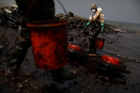 Työntekijät siivoavat Tongan tulivuorenpurkauksen aiheuttaman öljyvuodon tuhoja Anconissa Perun rannikolla.