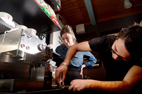 Antonio Lenzo valmistaa aitoa italialaista espressoa kahvikoneella Tampereen Kauppahallissa. Vera Campione seuraa työskentelyä taustalla.