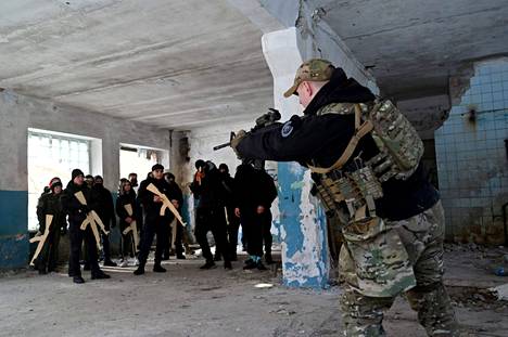 Sotilaskouluttaja opetti aseenkäyttöä puisin asekopioin varustautuneille siviileille hylätyssä tehtaassa Ukrainan Kiovassa 6. helmikuuta.