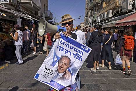 Israelin entisen pääministerin Benjamin Netanjahun kannattaja kuvattiin pitelemässä vaalimainosta ja megafonia Jerusalemissa perjantaina 28. lokakuuta. 