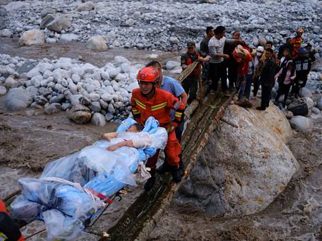 Pelastustyöntekijät kuljettavat maanjäristyksessä loukkaantunutta henkilöä hoidettavaksi Qinggangpingin kylässä Setšuanin maakunnassa Kiinassa syyskuun 5. päivä. 