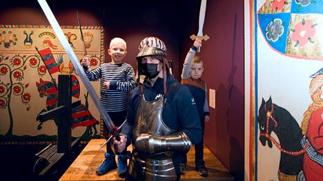 Emil ja Anton vahvistavat ritariryhmää takana, kun isä Vesa Ekman testaa haarniskaa Vapriikin museokeskuksen näyttelyssä.