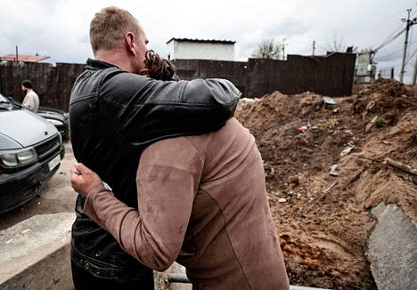 Mies lohdutti itkevää naista, kun poliisi etsi hänen poikansa ruumista kaivosta. Kuva otettiin lähellä Kiovaa sijaitsevassa Buzovan kylässä sunnuntaina 10. huhtikuuta. 