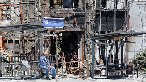 Mies istui tuhotun rakennuksen edustalla Mariupolissa Ukrainassa 9. toukokuuta.