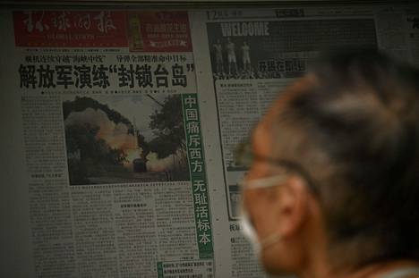 Mies luki sanomalehdestä juttua Kiinan sotaharjoituksista Pekingissä 8. elokuuta.