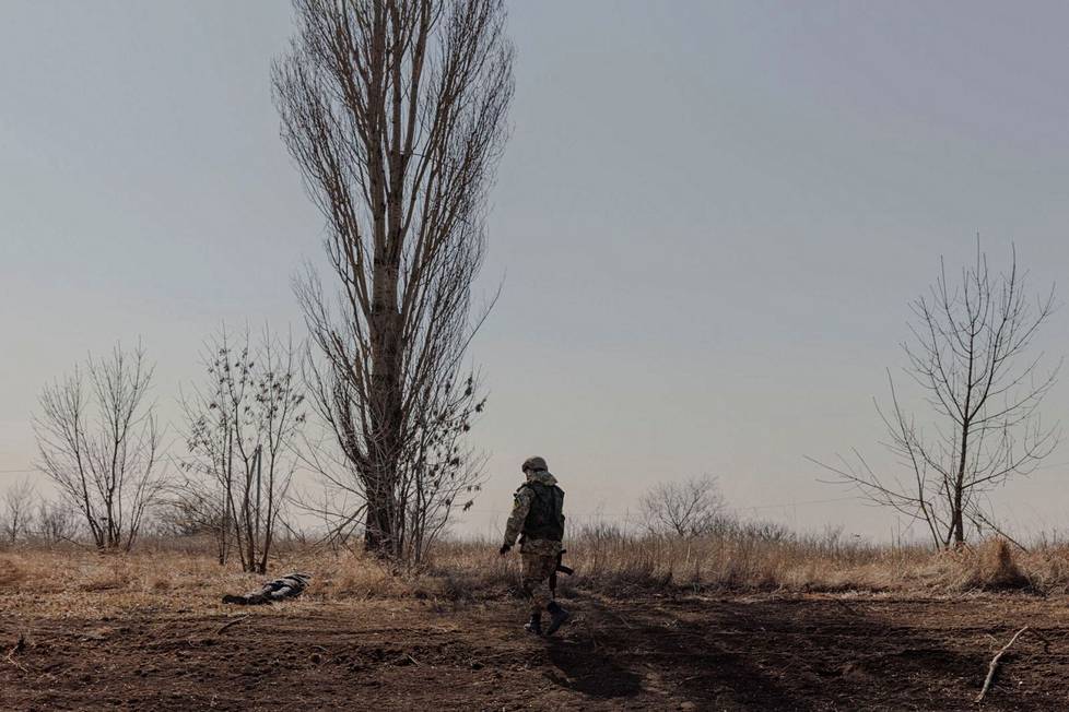 Ukrainan sotilas lähestyi siviilin ruumista Harkovan ulkopuolella 29. maaliskuuta. Ruumiiden kanssa on oltava tarkkana: Ukrainan mukaan Venäjän sotilaat saattavat miinoittaa ruumiita.