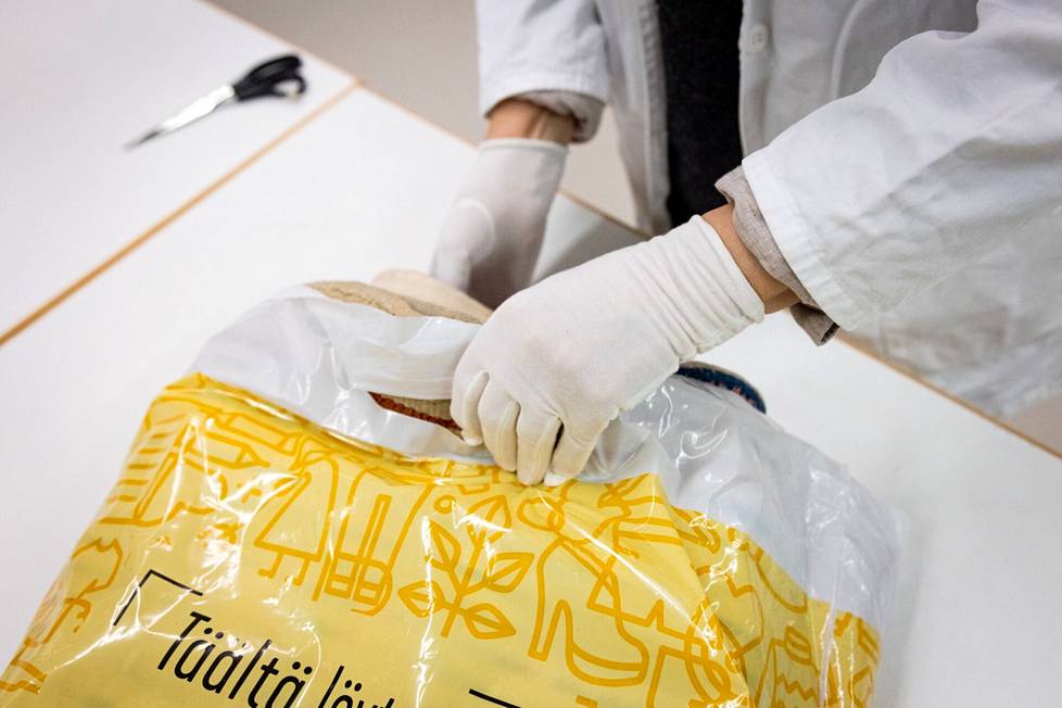 Ryijy on pakattu UFF:in muovikassiin, josta se otetaan Suomen käsityön museon konservointikeskuksessa ulos puuvillahansikkain. 