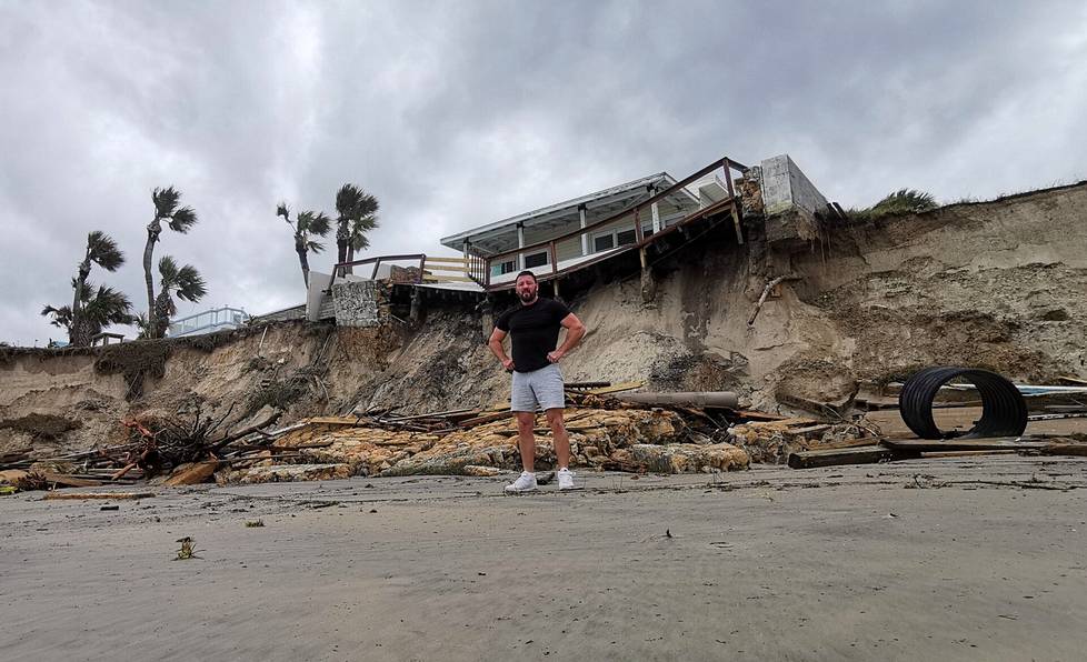 Markus Laine seisomassa hurrikaani Nicolen aiheuttamassa ”kraatterissa” Airbnb-asuntonsa edessä.