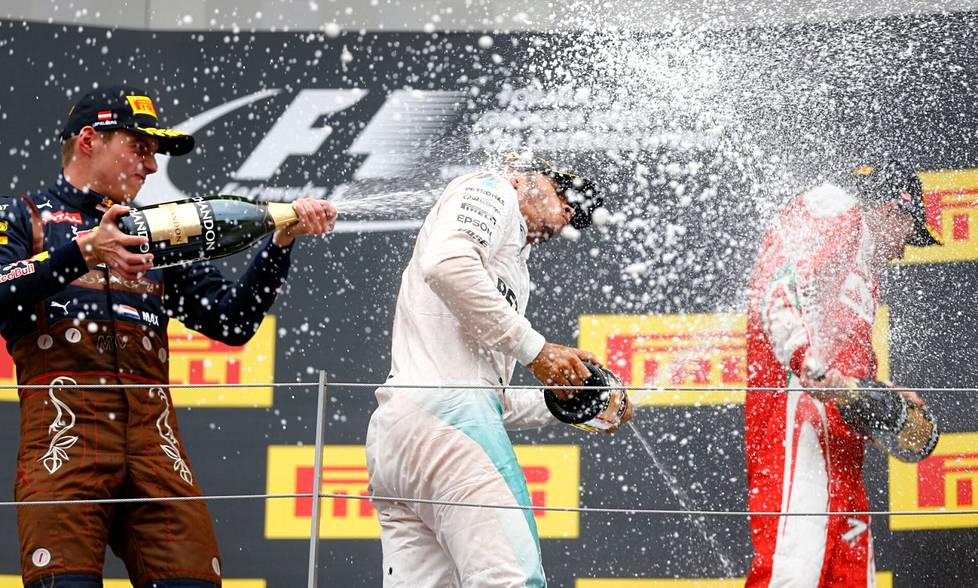 Max Verstappen (vas.) kuohutti vuonna 2016 Itävallan Spielbergissä juomaa Lewis Hamiltonin (kesk.) päälle. Kolmantena mukana tuolloin Ferrarilla ajanut Kimi Räikkönen.