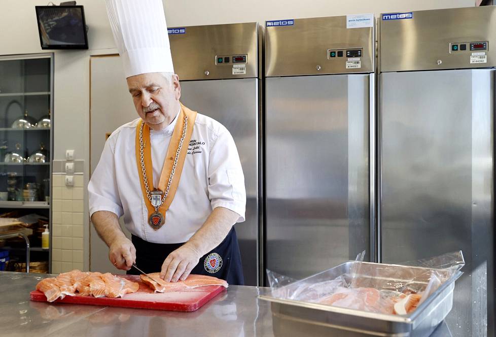 Porin kaupunginhallituksen keittiömestari Juhani Lahti käsittelee merilohta, jota tarjoillaan demarien kunnallisjärjestön illallisella. 