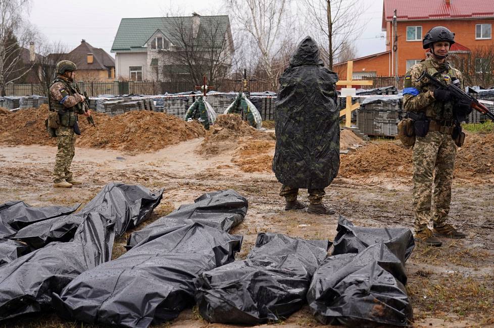 Ukrainan sotilaat vartiovat joukkohaudasta löydettyjä ruumiita Shymalissa Butšassa.