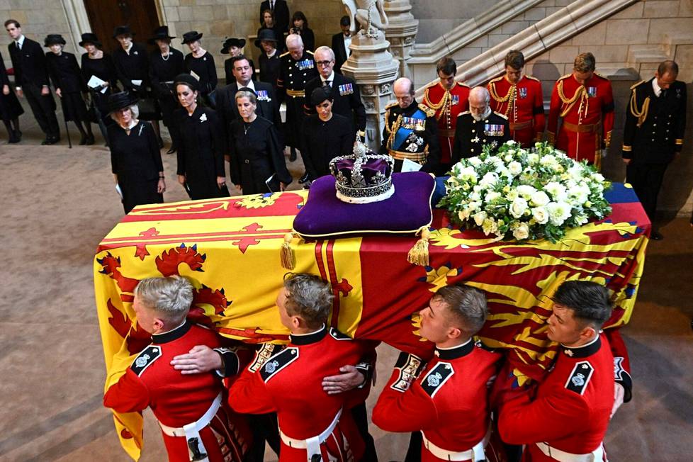 Kuningatar Elisabetia saatetaan haudan lepoon. Westminster Hallissa arkun toisella puolella seisovat rivissä mustiin pukeutuneina kuningatarpuoliso Camilla, prinssi Williamin puoliso, Walesin prinsessa Catherine, prinssi Edwardin puoliso, Wessexin kreivitär Sophie, prinssi Harryn puoliso, Sussexin herttuatar Meghan sekä prinssi Edward, Kentin herttua ja prinssi Richard, Gloucesterin herttua.